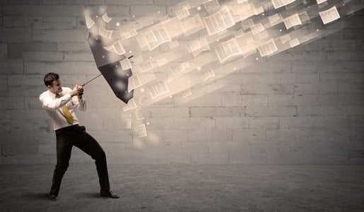 Business man protecting with umbrella against wind of papers concept