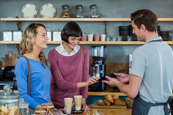 Customer making payment through payment terminal at counter in cafx96xA7