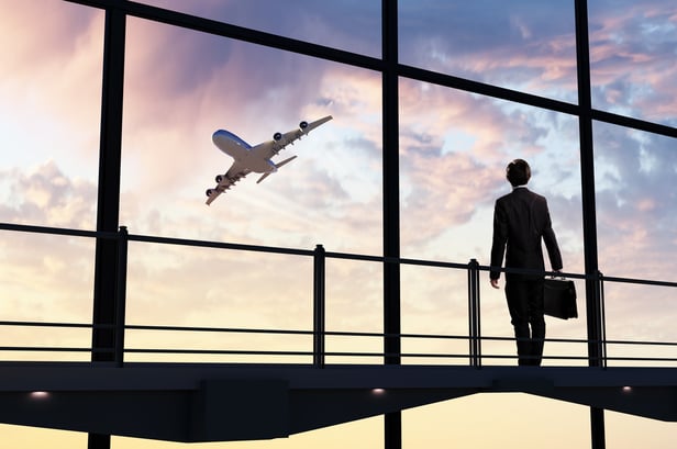 Image of businessman at airport looking at airplane taking off