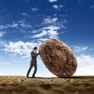 Image of businessman rolling a giant stone