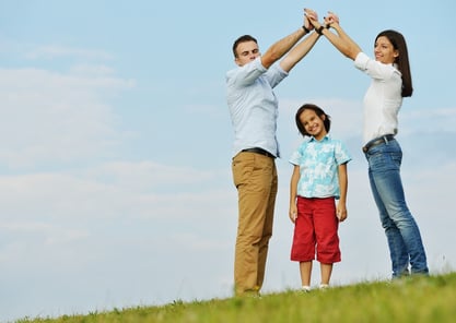 Young family on green summer grass meadow building dream new home